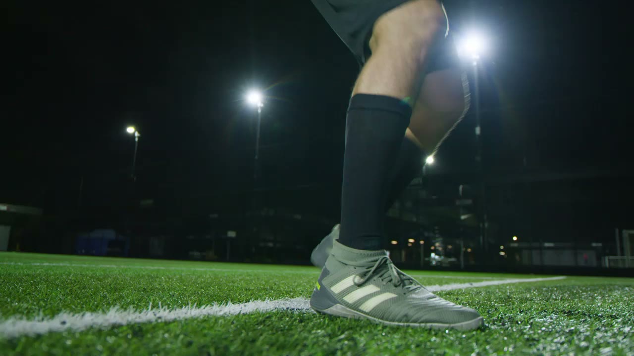 A player striking the ball under floodlights