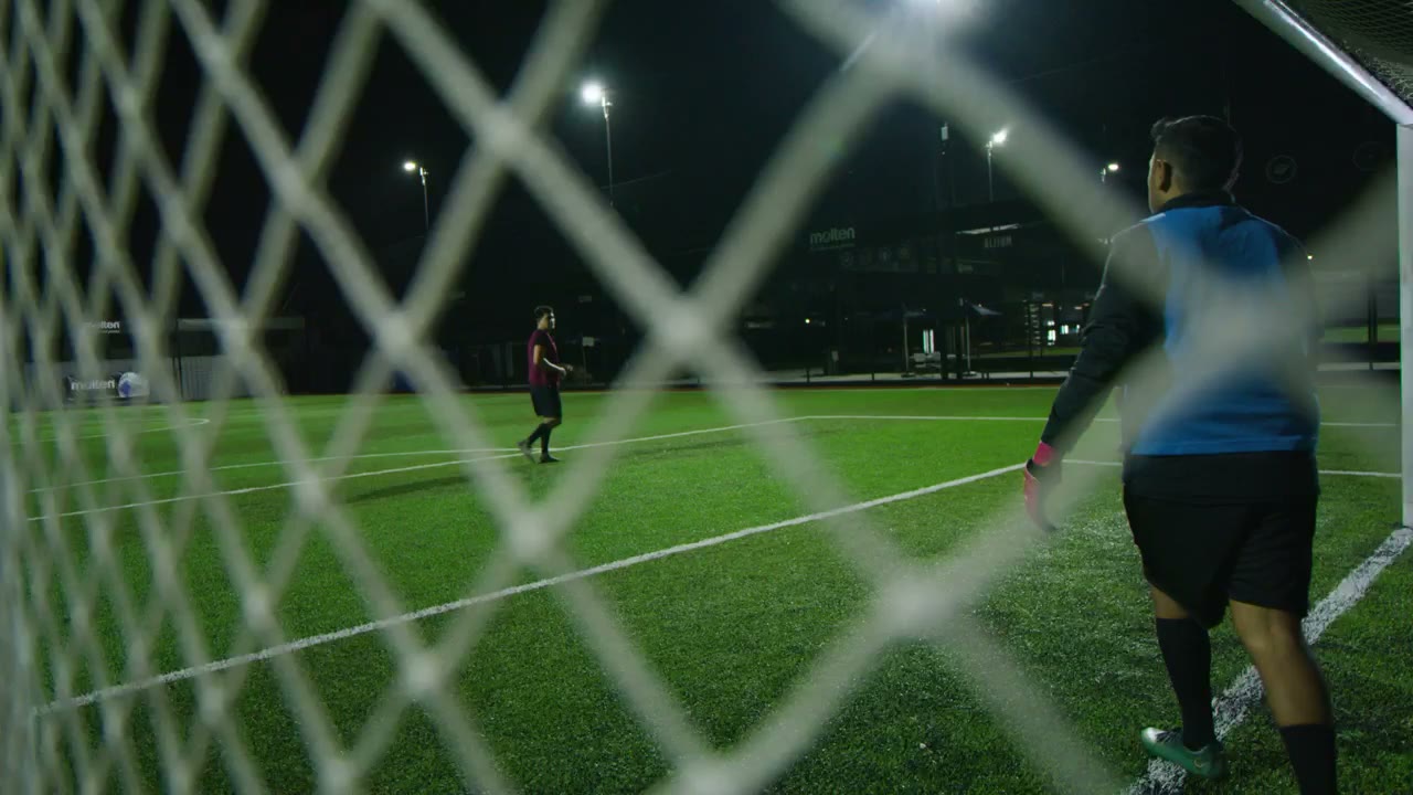 A goalkeeper seen through the net at night